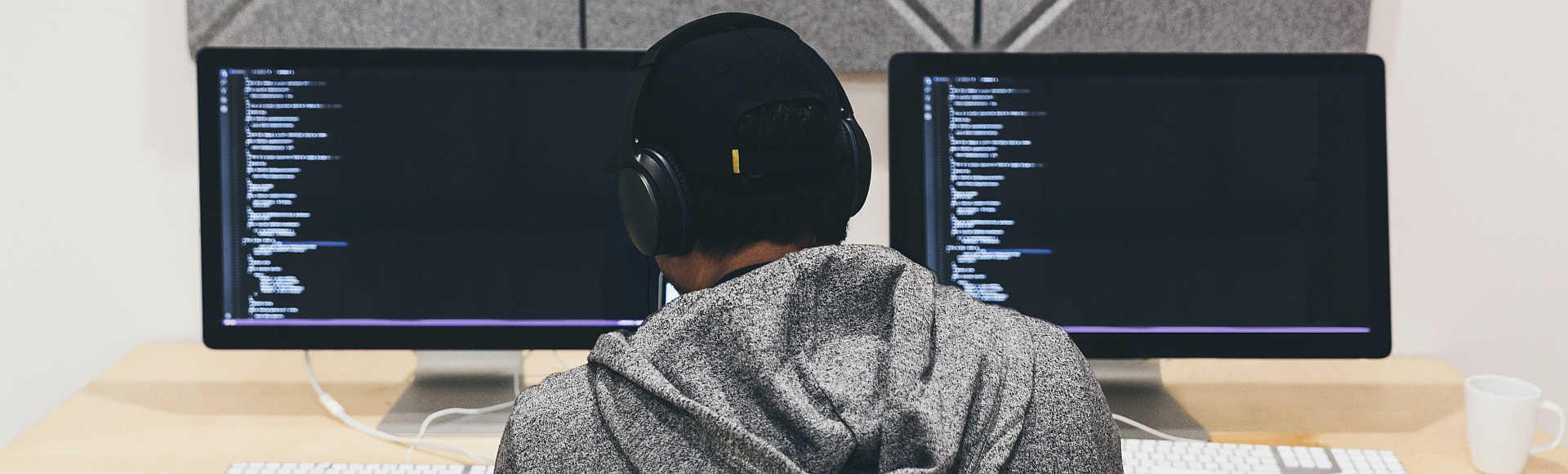 Focused Individual Reviewing Code on a Computer Screen at a Desk.